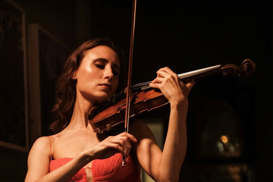 A woman with long brown hair playing a violin